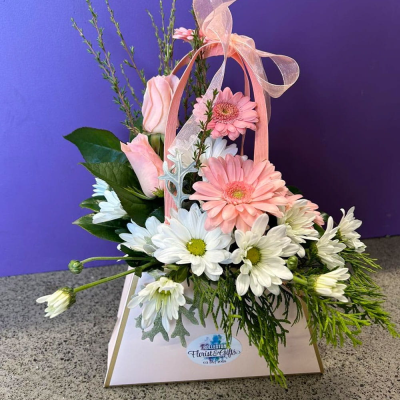 Sweet Blush Bag - A charming handle-style arrangement of soft pink gerberas, dainty roses and crisp white daisies, finished with an organza ribbon bow. Petite, pretty and full of gentle charm — lovely for new babies or a thinking-of-you gesture.