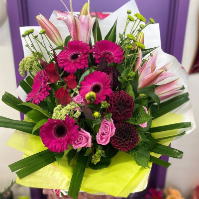 Berry Bright Bouquet - A bold, vibrant hand-tied bouquet packed with hot-pink gerberas, pink lilies, burgundy dahlias, roses and green button chrysanthemums. Rich, dramatic and full of life — a real showstopper for celebrations.